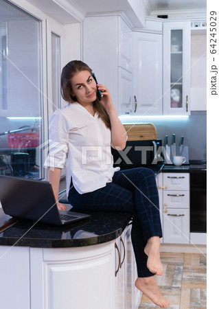 Girl in kitchen with laptop 64245029