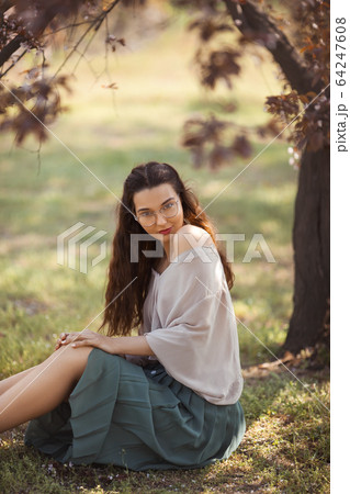 Woman Outdoors in Park Near Spring Blossom Tree Woman Outdoors in Park Near Spring Blossom Tree 64247608