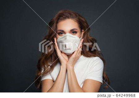 Young woman in face mask on dark gray background. 64249968