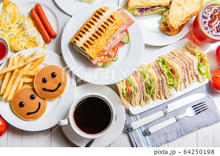 朝食、サンドイッチ、ハンバーガー、パンケーキ、卵、野菜、コーヒーで、ダイニングテーブル 64250198