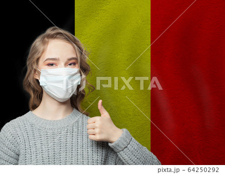 Happy woman in face mask holding thumb up  64250292