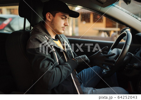 Man in car put on black gloves to protect himself Man in car put on black gloves to protect himself 64252043