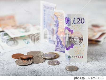Twenty pounds banknote with coin on light Twenty pounds banknote with coin on light 64253129