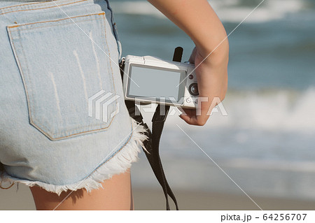 Close up hand of woman tourist holding camera on nature background. Female with camera over beach; freedom, travel concept; Free from copy space. Close up hand of woman tourist holding camera on nature background. Female with camera over beach; freedom, travel concept; Free from copy space. 64256707