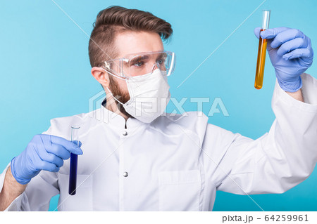 Covid-19, coronavirus, Vaccine development, pandemic, outbreak and medicine concept - Man scientist in flu mask and protective gloves holding a test tube. 64259961