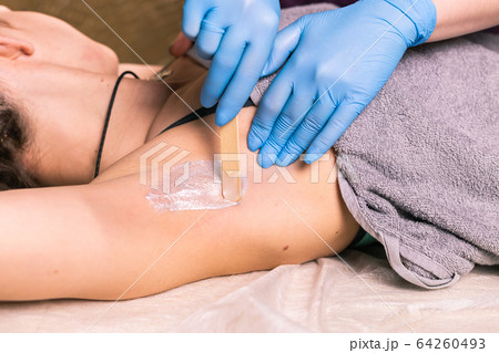 Waxing woman armpit. Salon wax beautician epilation procedure. Waxing female body for hair removal by therapist close up. Smooth underarm concept. 64260493