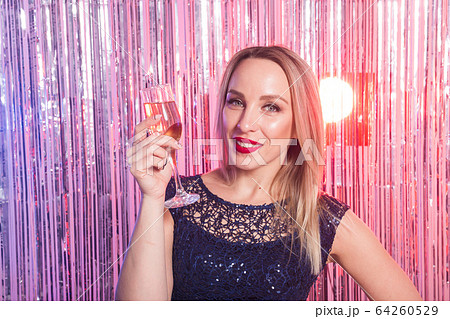 Party, drinks, holidays and celebration concept - smiling woman in evening dress with glass of sparkling wine over shiny background. Party, drinks, holidays and celebration concept - smiling woman in evening dress with glass of sparkling wine over shiny background. 64260529