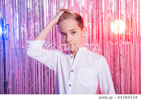 Awkward age and teenage concept - Portrait of teen boy at a party. Shiny background. Awkward age and teenage concept - Portrait of teen boy at a party. Shiny background. 64260534
