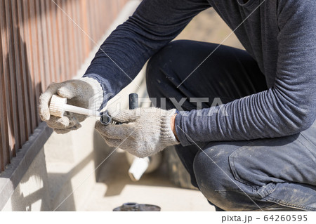 水道工事　接着剤を塗っている配管工 64260595