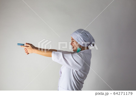 The girl in a medical coat holds a large syringe with blue liquid like a gun 64271179