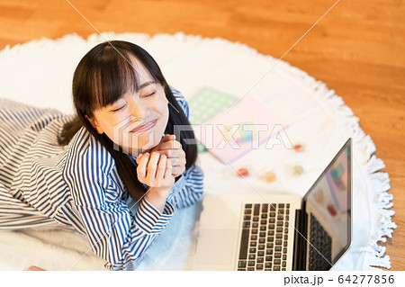 リビングで横になりながら、お菓子を食べる若い女性 リビングで横になりながら、お菓子を食べる若い女性 64277856