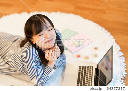 リビングで横になりながら、お菓子を食べる若い女性 リビングで横になりながら、お菓子を食べる若い女性 64277857