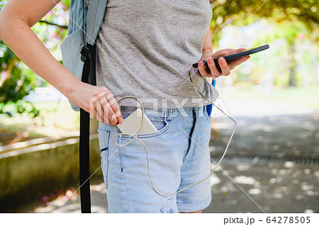 Female tourist connect smartphone to power bank 64278505