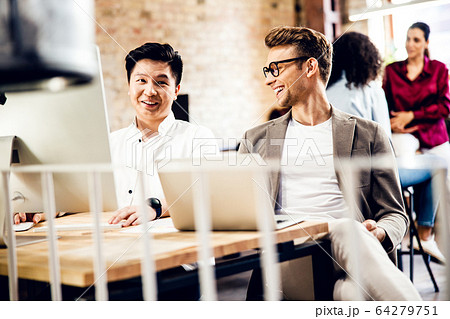 Cheerful male workers chatting and laughing in office 64279751