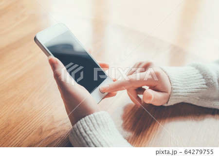 Women's hands use a smartphone for online shopping. 64279755