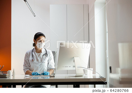 Caucasian doctor in medical mask and rubber gloves working at laptop 64280766