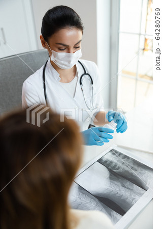 Pretty calm pediatrician in medical mask discussing about medicine in bottle 64280769