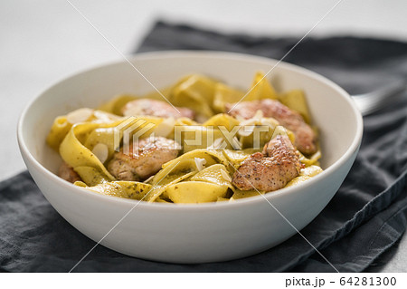 Pasta tagliatelle with chicken, pest and almonds in white bowl Pasta tagliatelle with chicken, pest and almonds in white bowl 64281300