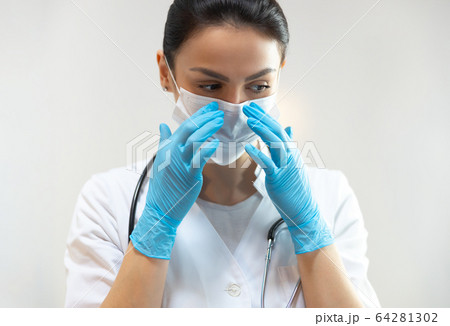 Caucasian young doctor in rubber gloves wearing medical mask Caucasian young doctor in rubber gloves wearing medical mask 64281302
