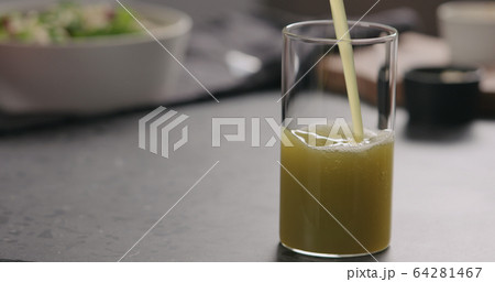 pour apple celery juice in glass on concrete countertop with copy space 64281467