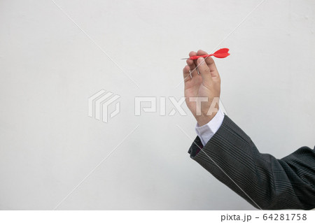 Business education success and target concept. Close up a hand is targeting the green dart arrow towards the center of dartboard. Business education success and target concept. Close up a hand is targeting the green dart arrow towards the center of dartboard. 64281758