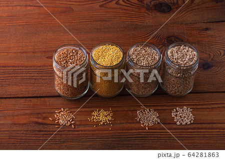 Cereal grains in glass jars on wooden background. Collection of different groats top view barley, oats, millet and wheat. Wholegrain foods with high fiber content flat lay. Healthy diet ingredients. Cereal grains in glass jars on wooden background. Collection of different groats top view barley, oats, millet and wheat. Wholegrain foods with high fiber content flat lay. Healthy diet ingredients. 64281863
