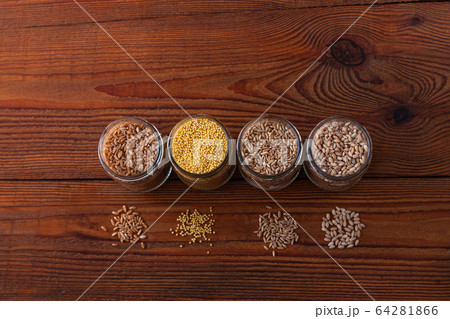 Cereal grains in glass jars on wooden background. Cereal grains in glass jars on wooden background. 64281866