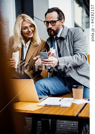Smiling woman pointing at a mobile phone Smiling woman pointing at a mobile phone 64282157