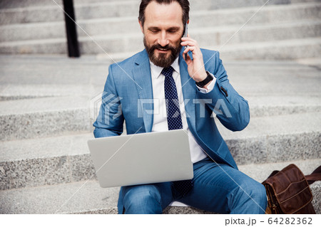 Smiling male entrepreneur working on a notebook 64282362
