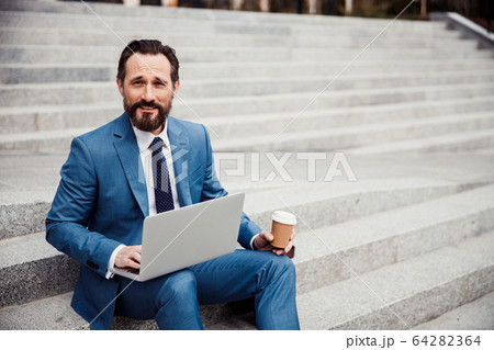 Pleased dark-haired Caucasian male entrepreneur looking forward 64282364