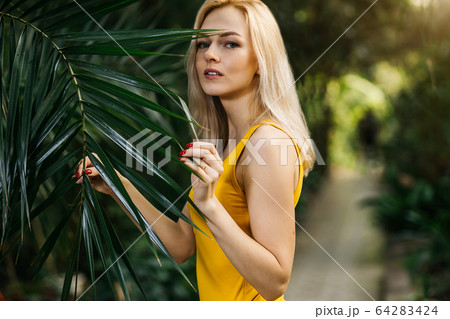 Woman in swimsuit on tropical plants background Woman in swimsuit on tropical plants background 64283424