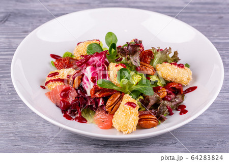 Salad with chicken fillet in bread crumbs, served with pecan nuts and fresh salad Salad with chicken fillet in bread crumbs, served with pecan nuts and fresh salad 64283824