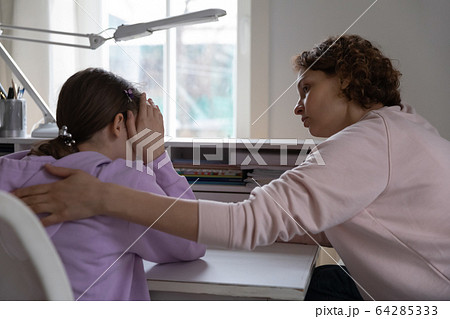 Worried mother talking comforting upset teen daughter at home Worried mother talking comforting upset teen daughter at home 64285333