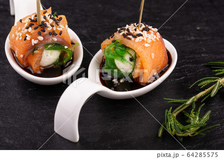 Canape salmon with cheese and sesame seeds on black background 64285575