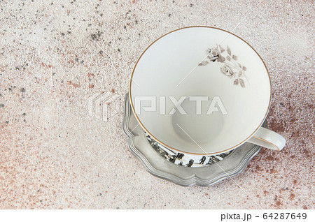 Antique tea mug on pewter coaster on concrete Antique tea mug on pewter coaster on concrete 64287649