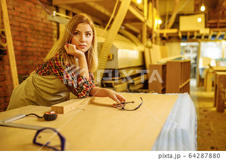attractive professional woodworker during work in factory 64287880