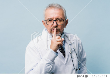 Portrait of a doctor showing silence gesture. Medical secret concept. 64289881