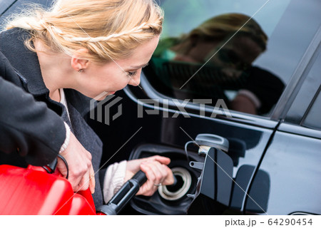 Woman filling car up with gas from the spare canister 64290454