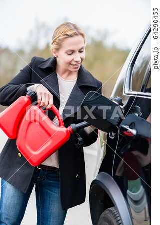 Woman filling car up with gas from the spare canister 64290455
