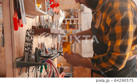 A man worker takes glasses from the stand in the carpentry workshop 64290575