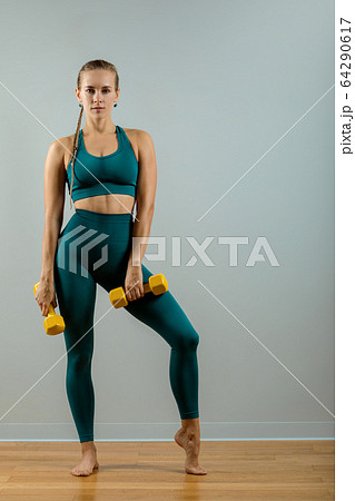 Athletic woman with dumbbells in hands on a gray background, fitness banner, fitness motivation. Photo of a muscular fitness model working out with dumbbells on a gray background. Athletic woman with dumbbells in hands on a gray background, fitness banner, fitness motivation. Photo of a muscular fitness model working out with dumbbells on a gray background. 64290617