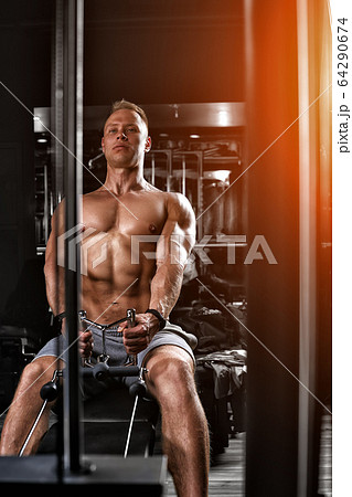 Handsome bodybuilder doing heavy weight exercise for the back on a simulator. Athletic body, preparation for the summer season. Fitness motivation. Copy space, sport banner Handsome bodybuilder doing heavy weight exercise for the back on a simulator. Athletic body, preparation for the summer season. Fitness motivation. Copy space, sport banner 64290674