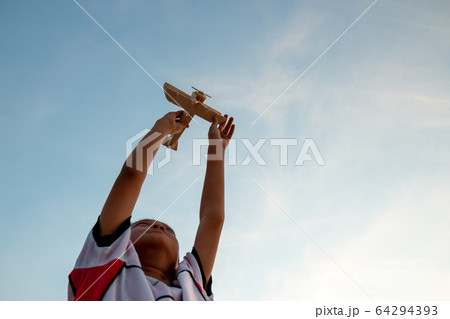 Happy kid playing with toy wooden airplane against Happy kid playing with toy wooden airplane against 64294393
