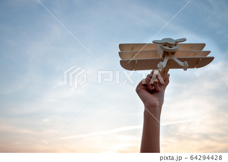 Happy kid playing with toy wooden airplane against Happy kid playing with toy wooden airplane against 64294428