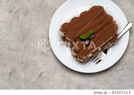 Classic tiramisu dessert on ceramic plate on light grey concrete background Classic tiramisu dessert on ceramic plate on light grey concrete background 64307413