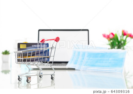 Credit card in shopping cart front of laptop 64309316