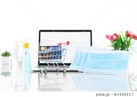 Credit card in shopping cart front of laptop 64309317