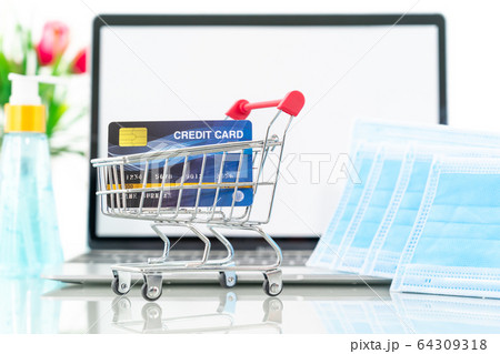 Credit card in shopping cart front of laptop 64309318