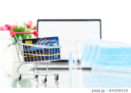 Credit card in shopping cart front of laptop 64309319