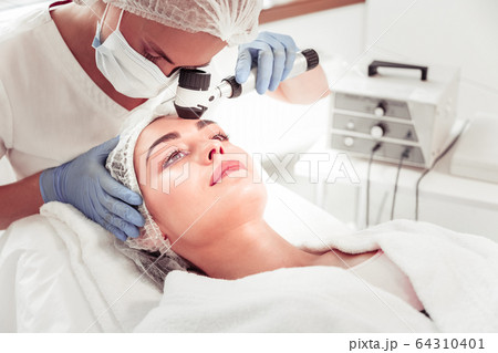 Woman having deep face cleansing visiting cosmetologist Woman having deep face cleansing visiting cosmetologist 64310401